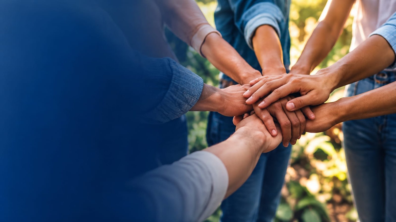 Grupo de personas uniendo sus manos en símbolo de comunidad y solidaridad